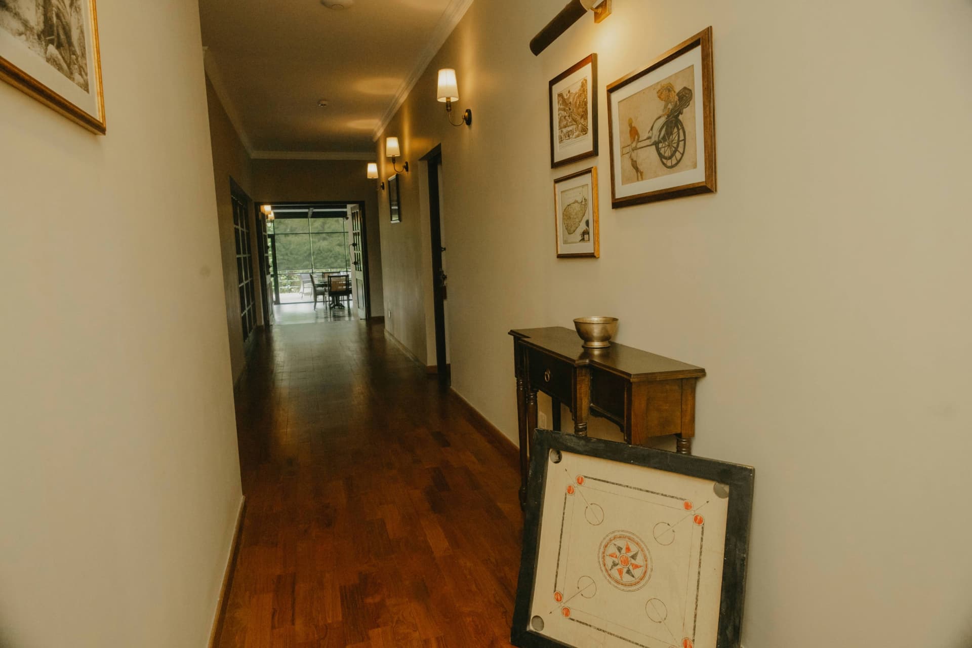 A warm hallway with framed artwork opening toward greenery
